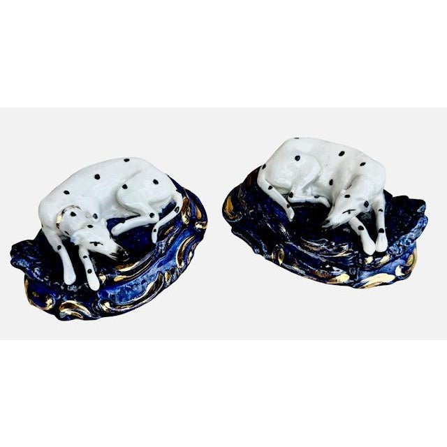 A handsome pair of antique English Staffordshire Dalmatian dog figurines. The figurines mirror each other and rest on a...