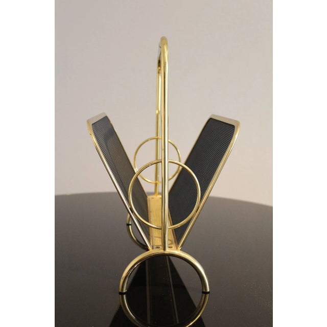 Magazine rack in brass and black lacquered metal, Italy 1970s, the structure is in brass, while the sides are in metal...