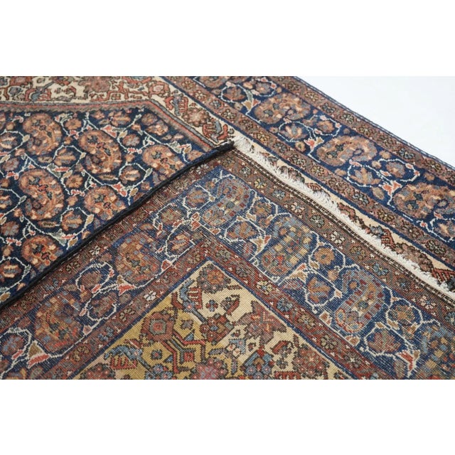 The navy sub-field shows offset rows of one-way botehs in red, green and sand, on slender trailing ecru vines, while the...