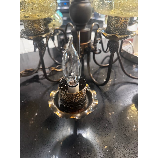 Ten light vintage hurricane style chandelier with amber crackle glass chimneys and a dark wood frame, chandelier arms are...
