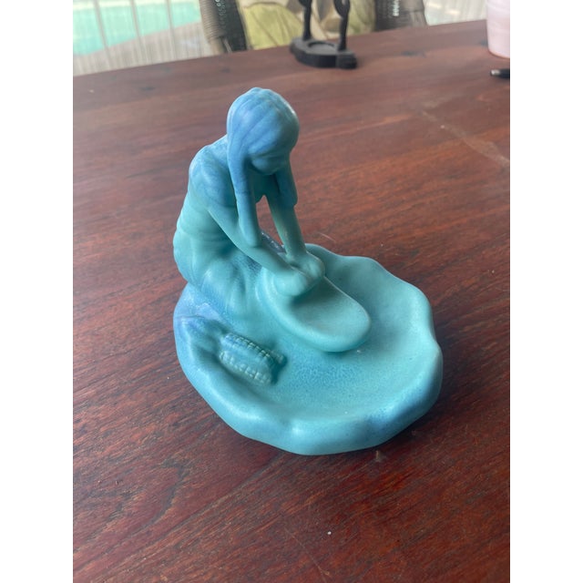 This vintage Van Briggle Pottery figurine depicts a Native American Indian girl grinding corn, showcasing a beautifully...