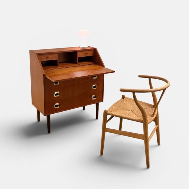 Danish secretary produced during the 1960s. executed in teak with three drawers, a fall-front writing section and an upper...