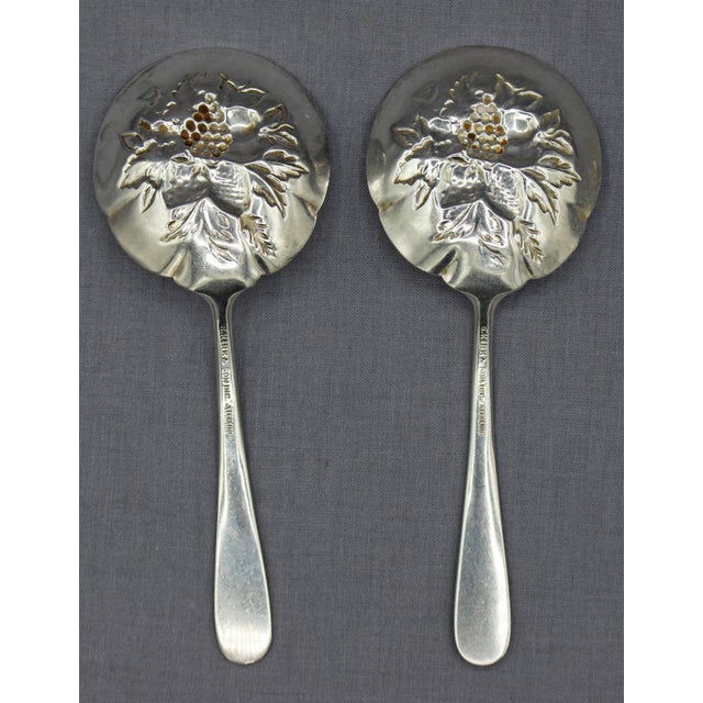 Pair of S. Kirk & Sons sterling silver repousse bon bon spoons, 1924. Shaped bowls decorated with berries & bright cut...