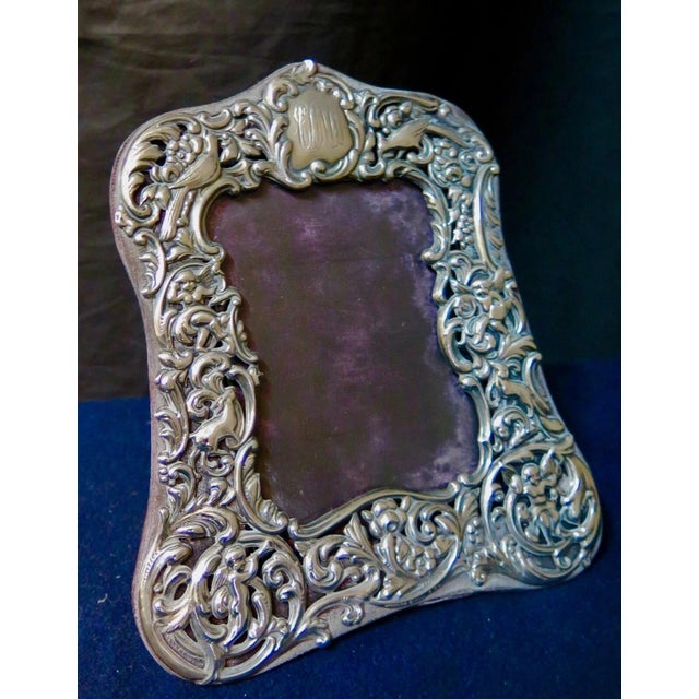 This vintage early 20th century table picture frame is designed in highly decorated sterling silver. This silver work...