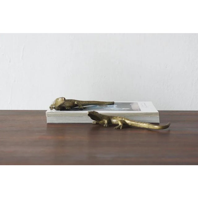 The figurine depicts a lizard in a realistic pose with its tail outstretched and limbs spread, as if it were in motion....
