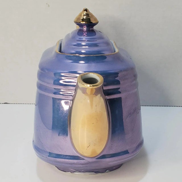 Periwinkle blue Lustreware teapot with gold accents, featuring a ridged design and curved detailing for a touch of...