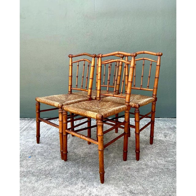 This set of four vintage bamboo-style wood and cane chairs beautifully captures the whimsical elegance of faux bamboo...