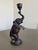 The bronze sculpture depicts an elephant standing on its hind legs to raise a candle holder. The artifact is of Eastern...
