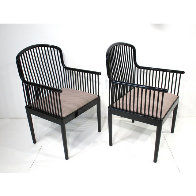 A pair of black lacquer wooden Andover armchairs with upholstered seat bottoms and having a unique wood dowel styled...