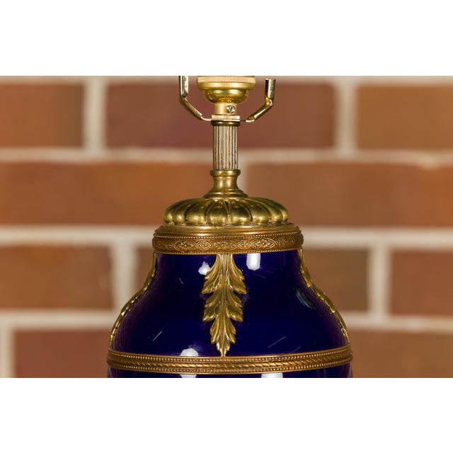 A French cobalt blue porcelain vase from the 19th century mounted into a table lamp with gilded foliage décor and custom...