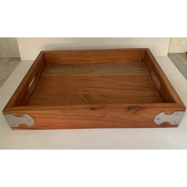 Solid stained wood tray with polished nickel shaped bracket accents on corners. Has cut out handles for ease of use and is...
