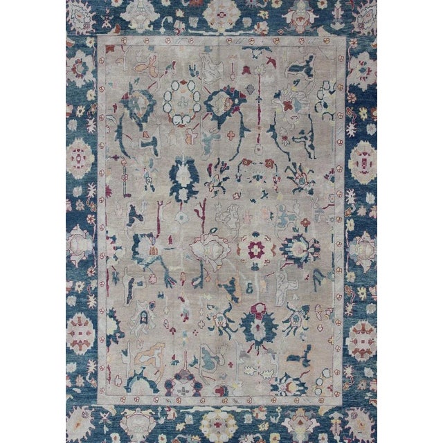 Oushak rug from Turkey with floral blossom all-over design rendered in gray, blue, ivory, and red tones. Keivan Woven Arts...