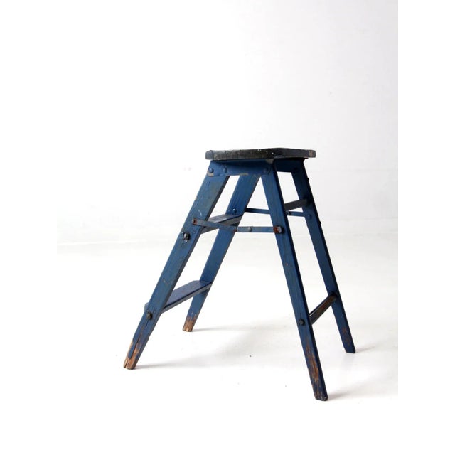 This is a vintage wooden step ladder. Cerulean blue paint colors the two run step stool, as metal hinges close and open...