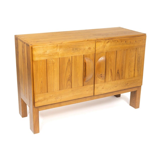 The fronts are composed of vertical slats of solid elm set within a wide frame; the handles, two half-moons carved from a...