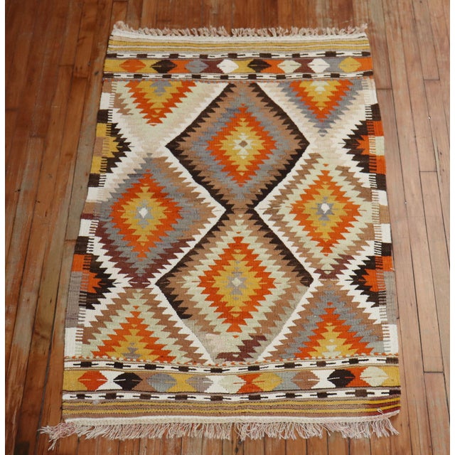 A handmade Turkish Kilim throw rug from the mid-20th century. Accents in light green, burnt orange, gray, brown Measures:...