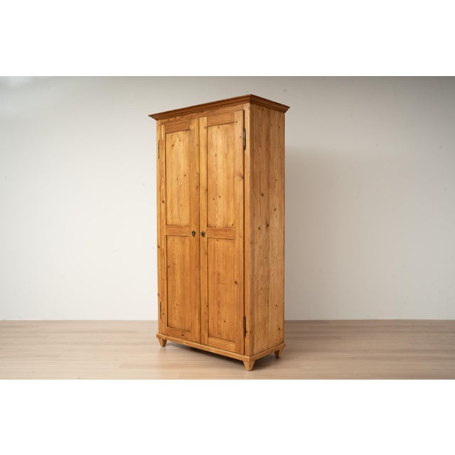 An antique wardrobe made of solid pine, originating from Germany and dating to the late 19th century. The wardrobe offers...
