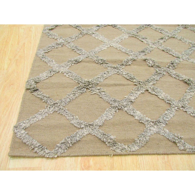 A handwoven wool flatweave, made in India and measuring 6' x 9'. Geometric drawing across the field. Flatweaves carry no...