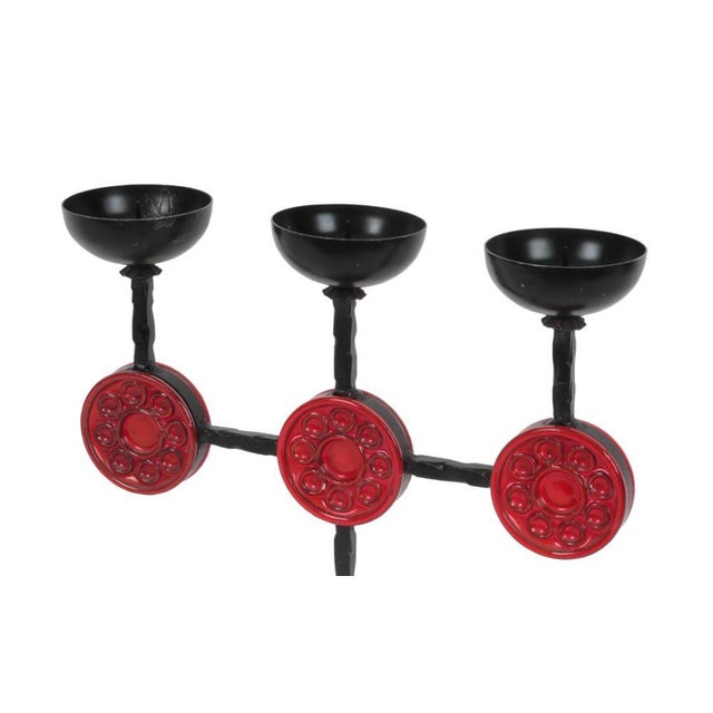 A 1960's Swedish three-candle candelabra in black iron and red glass disks. The candelabra is attributed to Erik Hoglund,...