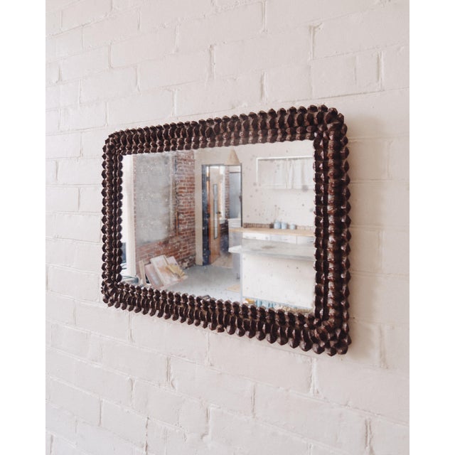A rectangular wall mirror with a fully wrapped pinecone frame, composed of densely applied natural elements over a wood...