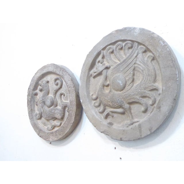 This pair of cast stone decorative tiles hang on the wall.