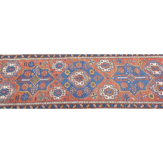 This short-pile, east Caucasian village scatter presents a soft rust-red abrashed field centred on a medium blue hexagon,...