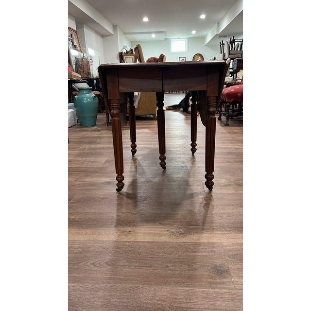 This vintage rustic wood drop-leaf dining table features a rich patina, rounded drop-down leaves, elegant turned legs, and...