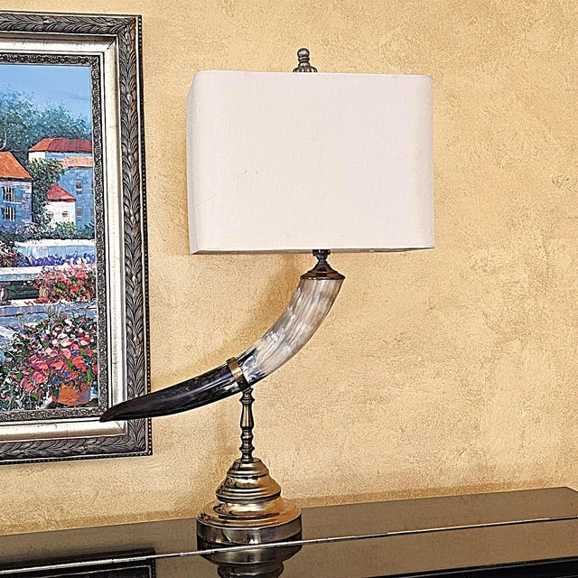 Distinctive vintage table lamp featuring a sculptural faux animal horn mounted on an ornate brass-tone metal pedestal and...