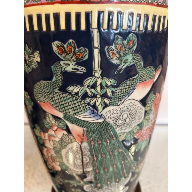 Grand beautiful and large pair of porcelain Chinoiserie style lamps having a black ground and ornate bird and foliage...