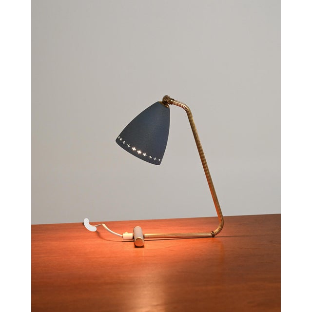 Fluted brass frame with an adjustable conical shade in painted metal and perforated edge. Designed by Eric Wärnå, Sweden,...