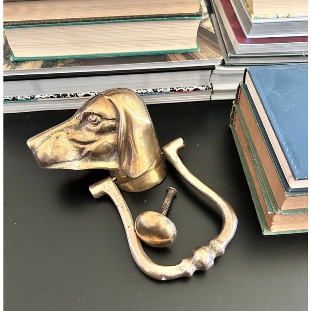 A solid brass dog door knocker with a sculptural hound or sporting-dog head, warm aged patina, and classic estate-style...