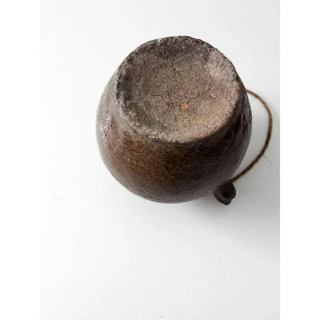 An antique utilitarian earthenware water pot with a rounded, grounded form and rich brown glaze. The small pouring spout,...