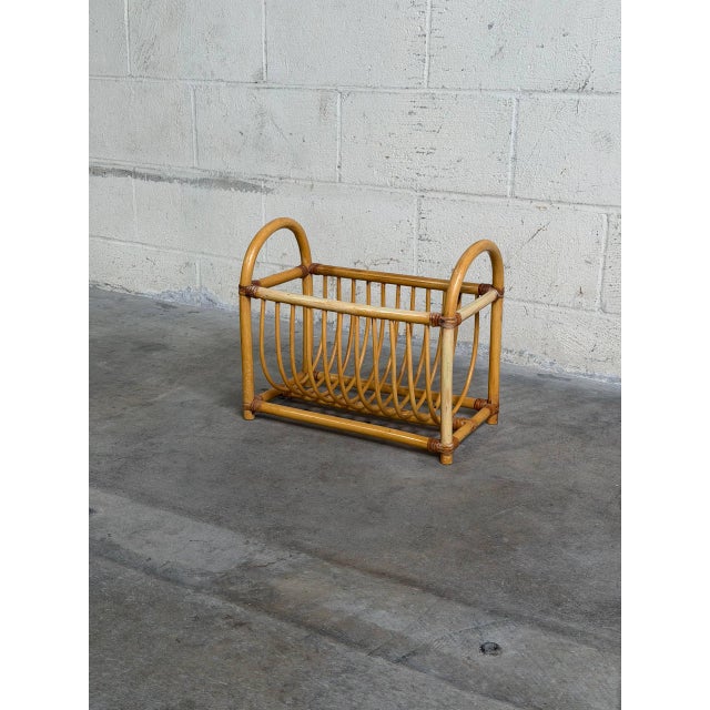 Vintage rattan magazine rack featuring a beautifully curved woven design with bentwood-style arches and warm natural...