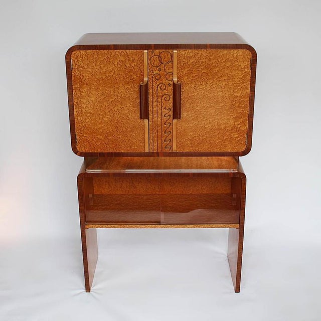 A 1950s cocktail cabinet consisting of two integral sections with central mirrored panel in peach glass. Carved, stylised...