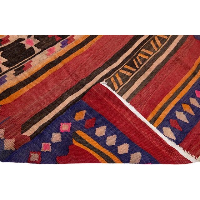 Beautiful vintage Turkish Kilim hand-knotted wool rug with a red field. This piece has a purple frame and multicolor...