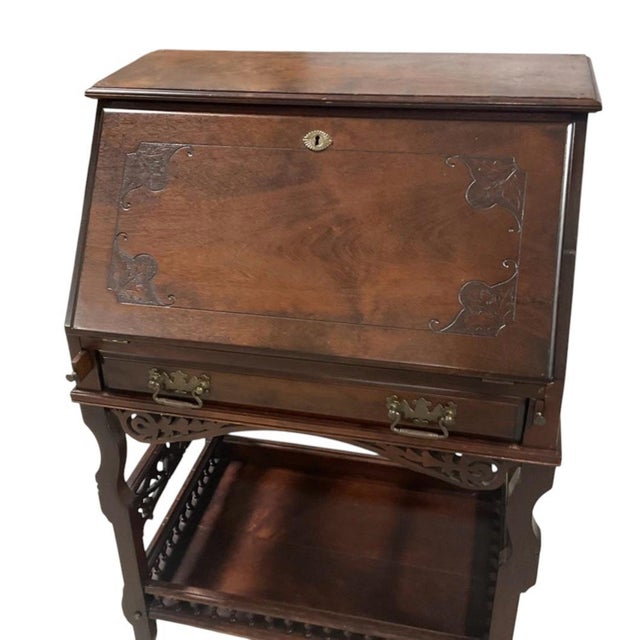 A vintage early 20th-century mahogany drop-front secretary desk designed in the Chippendale Revival taste with Queen Anne...