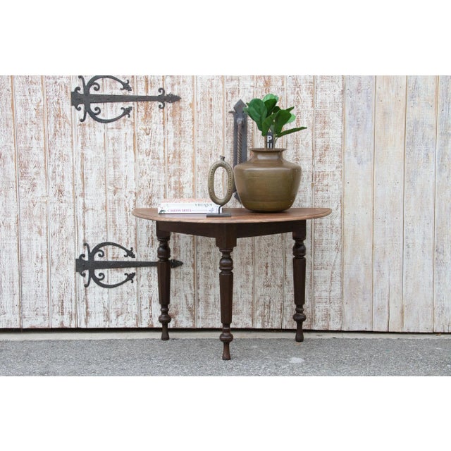 Charming antique colonial demilune console table standing on three rounded legs. This antique console has a painted brown...