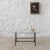 Elegant coffee table with a black lacquered metal base and glass top. The magazine rack consists of parallel brass bars....
