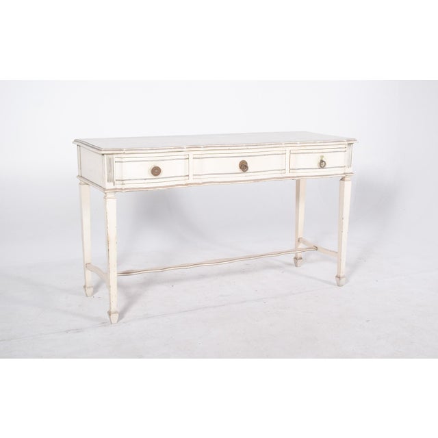 White painted console. The wooden structure has elegant lines with a slight undulation on the front, where three...