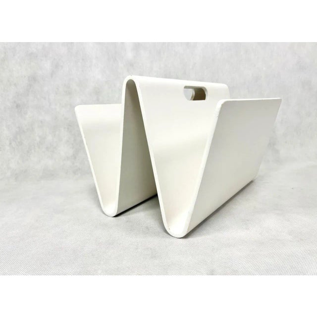 Magazine rack in very good condition. Made of bent plywood, painted white. Surface with visible signs of use. This piece...