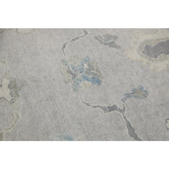 This modern Turkish Oushak rug is a stunning piece of art that has been handwoven using traditional techniques by skilled...