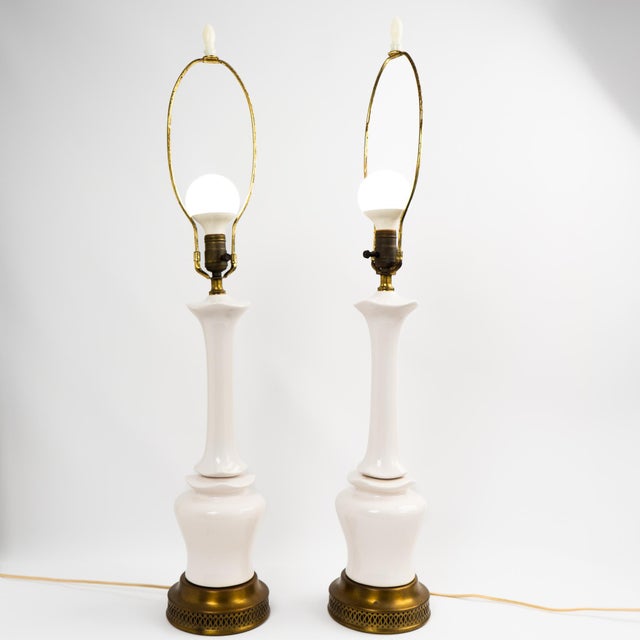 A pair of statuesque mid-century ceramic lamp bases in a soft off-white glaze with Chinoiserie-inspired detailing....