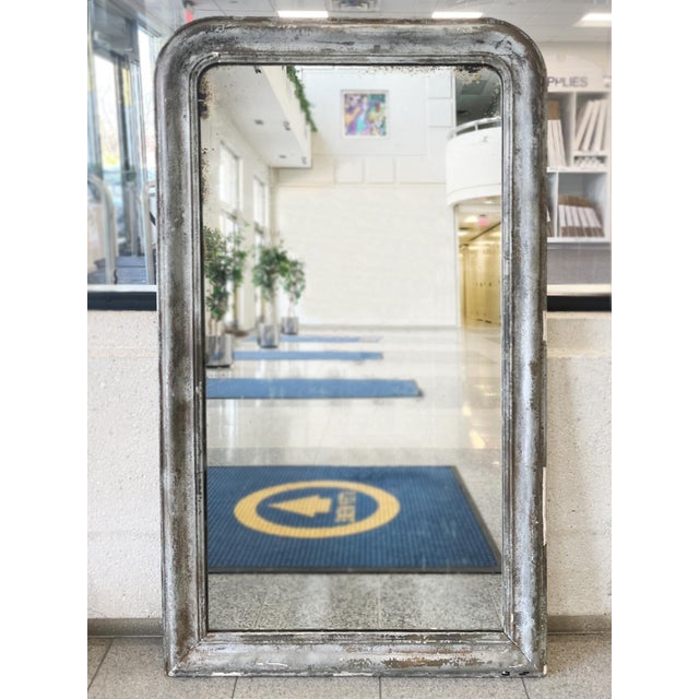 Hand-crafted in the 19th Century in France, this antique vertical wall mirror has a silver gilt frame with an ogee bevel....