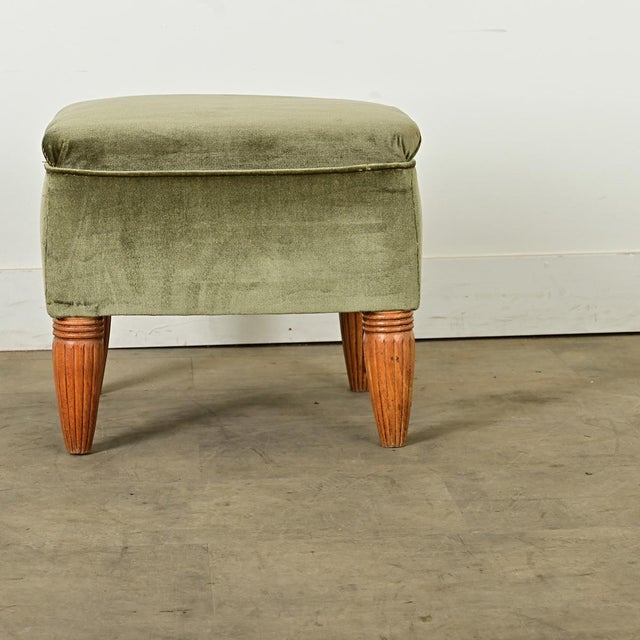 Dimensions: 18 ¼” H x 20 ½” W x 19 ¾” D A pretty and plush footstool from the Art Deco period with elegant hand-carved...