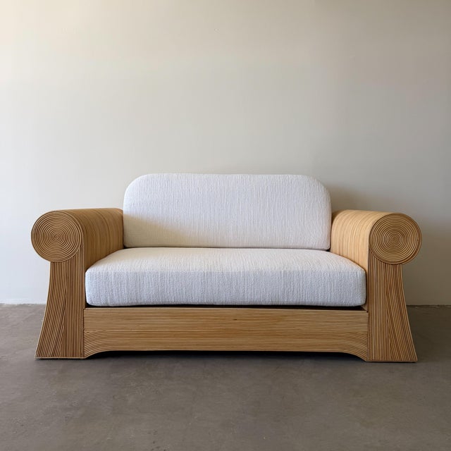 Vintage 1970s pencil reed loveseat featuring a sculptural bamboo frame and newly upholstered cushions in an off-white...