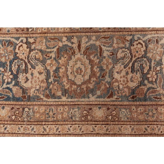 An early 20th century Persian Tabriz rug, the abrashed camel field with an allover lattice of beige and brown strap work...