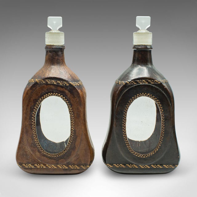 This is a set of four antique spirit bottles. An English, leather dressed glass decanter, dating to the Victorian period...
