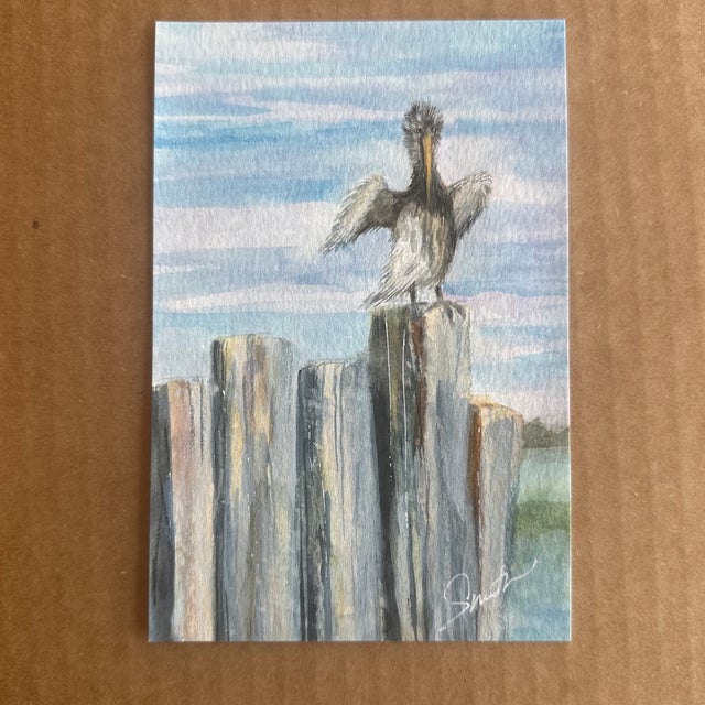 Experience the tranquility of coastal life with this beautiful watercolor of a seabird perched confidently on weathered...