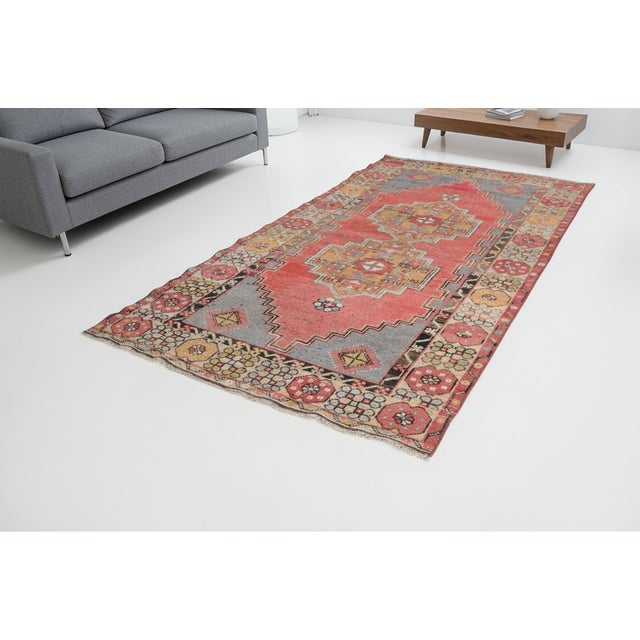 This is a vintage Turkish Oushak rug from the Mid 20th Century. The piece was hand-knotted.