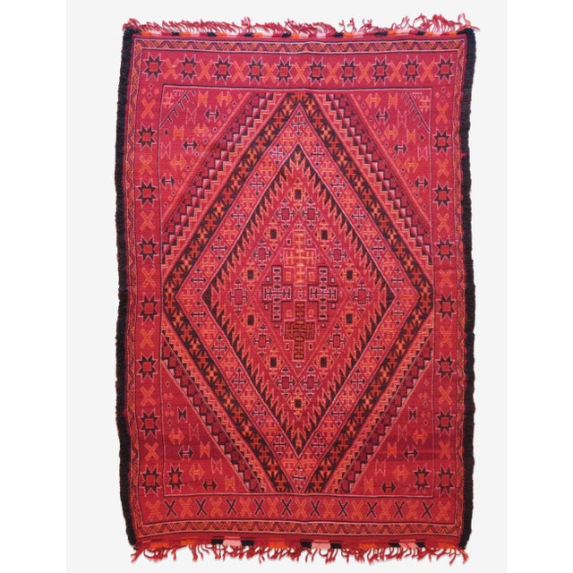 Immerse your space in the vibrant heritage of Morocco with this striking red collectible rug. Hand-woven by skilled women...