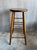 Vintage Late 20th Century wooden bar stool. This stool features a round seat, 3 rows of leg stretchers, and dark stain...